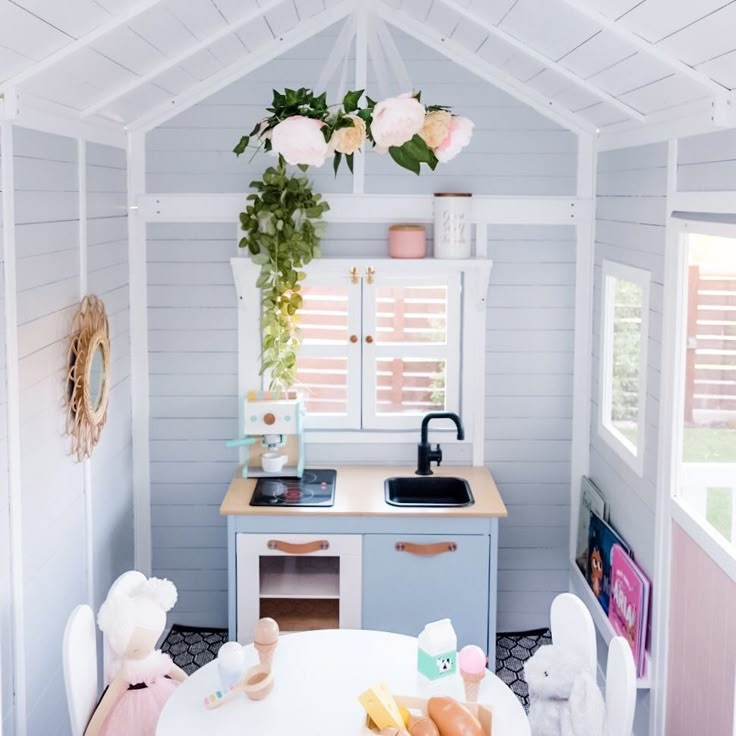 a white table and chairs in a small room with flowers hanging from the ceiling above it