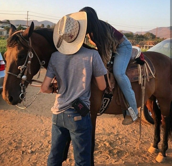 a man is standing on the back of a horse while another man stands next to him