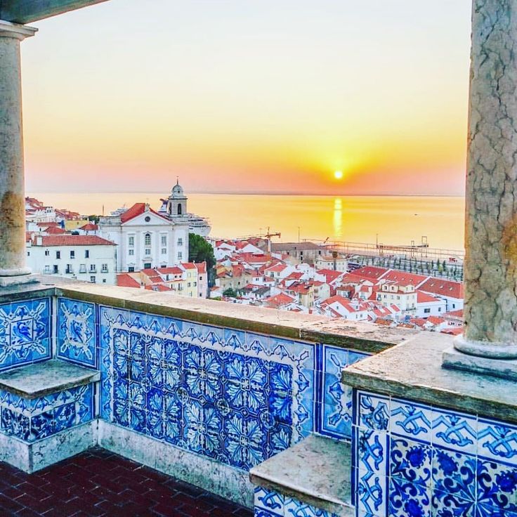 the sun is setting over a city with blue and white tiles on it's walls