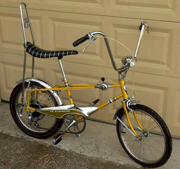 a yellow bicycle parked in front of a garage door next to a wall with a black and white stripe on the handlebars