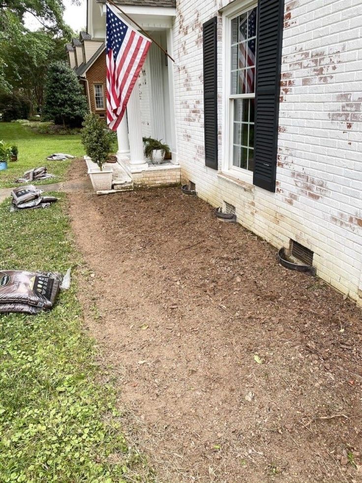 an american flag hanging on the side of a brick house with junk strewn around it