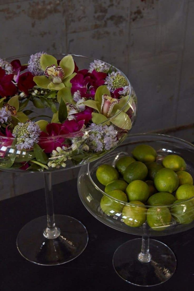 two glass bowls with flowers and limes in them