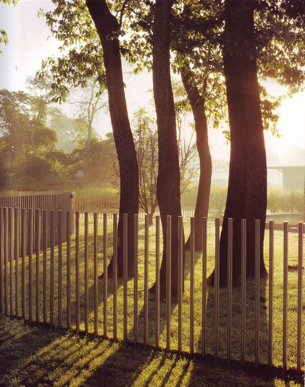 the sun shines through some trees behind a fence