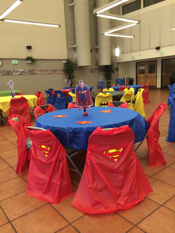 a room filled with tables and chairs covered in superman capes