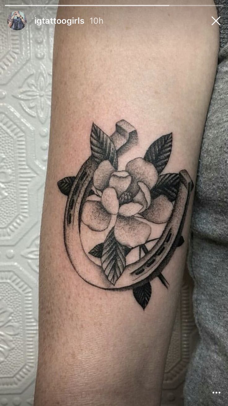 a black and white photo of a flower tattoo on the right arm, with leaves around it