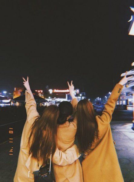 two young women are walking down the street with their arms in the air