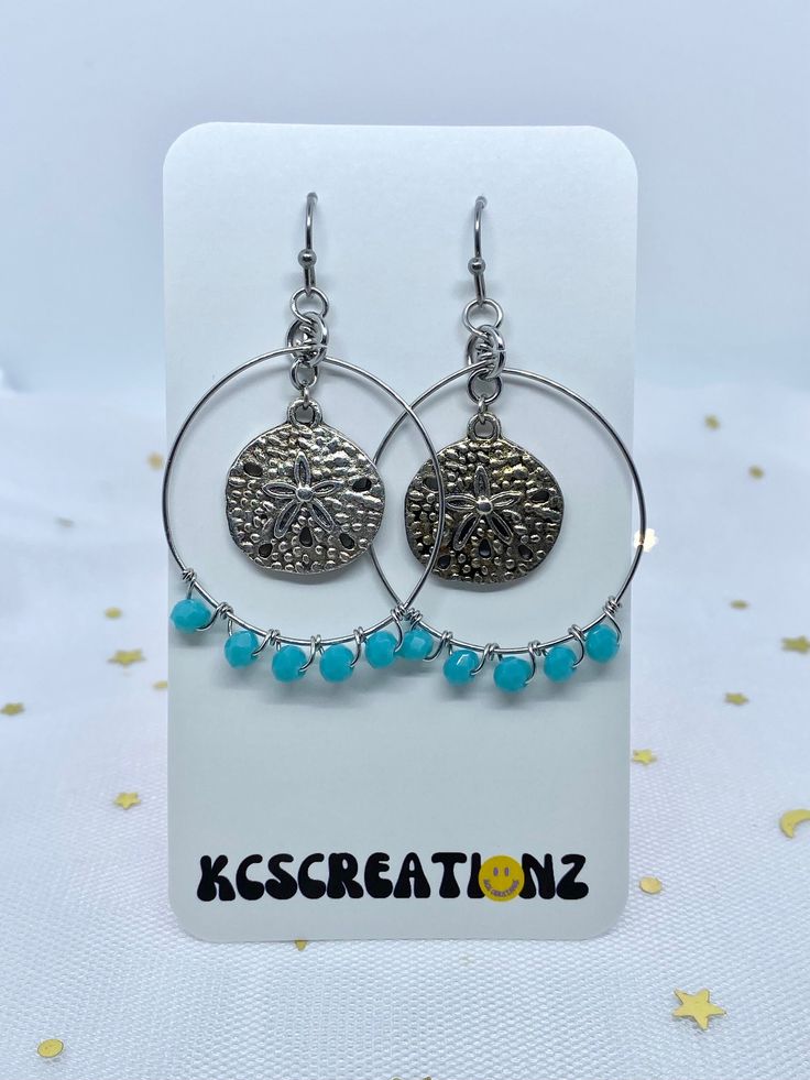 A stunning pair of sand dollar hoop earrings 🌟 LENGTH: 1.75 inches MATERIALS: Silver plated charms, stainless steel jump rings, stainless steel wire, faceted glass beads, stainless steel ear hooks. **Stainless steel is hypoallergenic and tarnish resistant which makes these earrings perfect for anyone with sensitive ears! SHIPPING: FREE to U.S. I'll take care of the shipping cost for you! All orders ship with USPS Ground Advantage (3-7 days delivery time). I will send your package out within 2-3 Nickel Free Sterling Silver Jewelry For Beach, Round Metal Earrings For The Beach, Handmade Jewelry With Round Beads For Beach Season, Metal Earrings For Beach In Summer, Sterling Silver Dangle Jewelry For Beach, Nickel Free Silver Jewelry For The Beach, Hypoallergenic Silver Jewelry For Beach, Metal Beaded Earrings For Summer, Trendy Adjustable Dangle Hoop Earrings