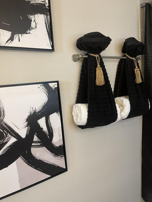 two black and white towels hanging on the wall next to pictures with gold tassels