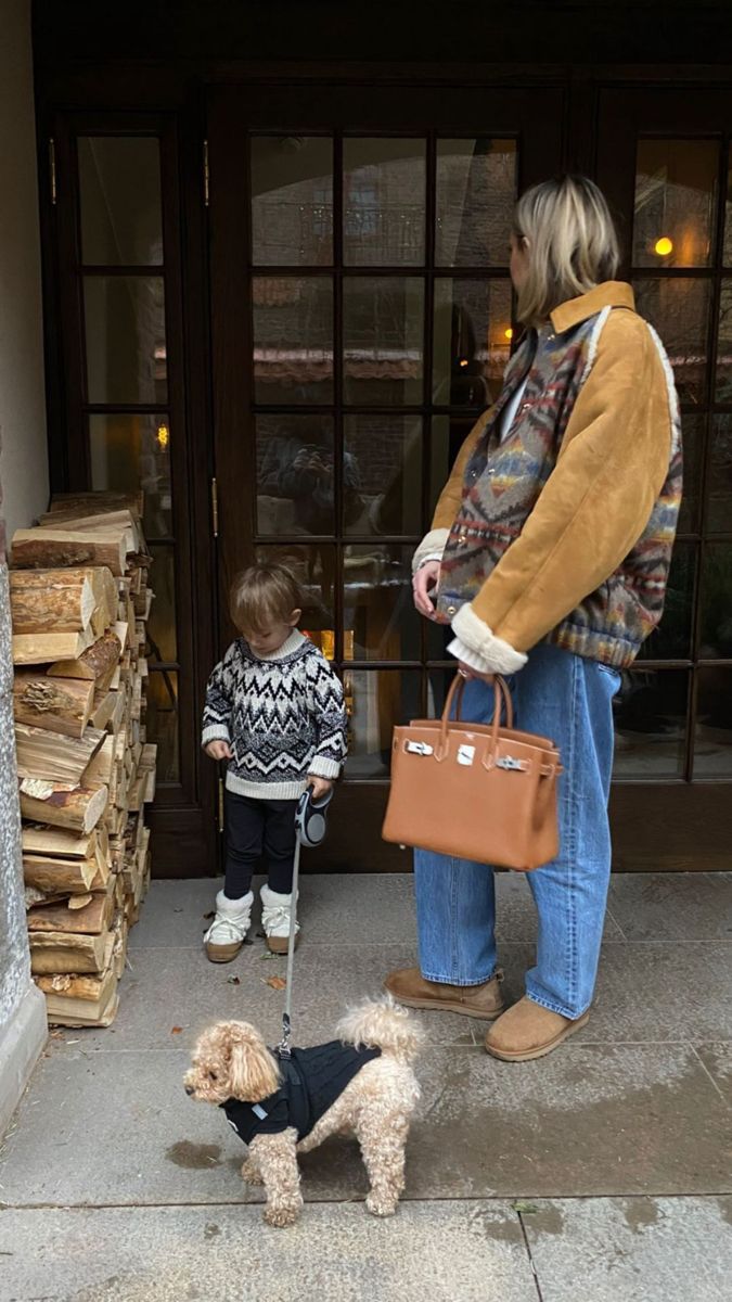 a woman and her child are walking their dog on the sidewalk in front of a building