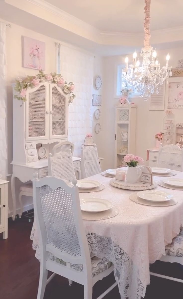 a dining room table with white chairs and a chandelier