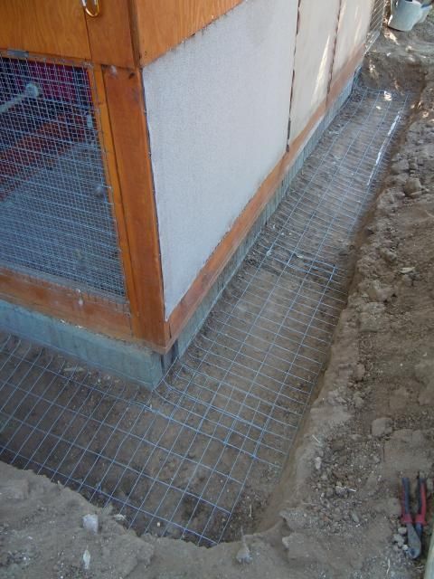 a building that is under construction with some wire on the ground and concrete in front of it