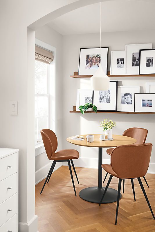 a dining room table with chairs and pictures on the wall above it in an apartment