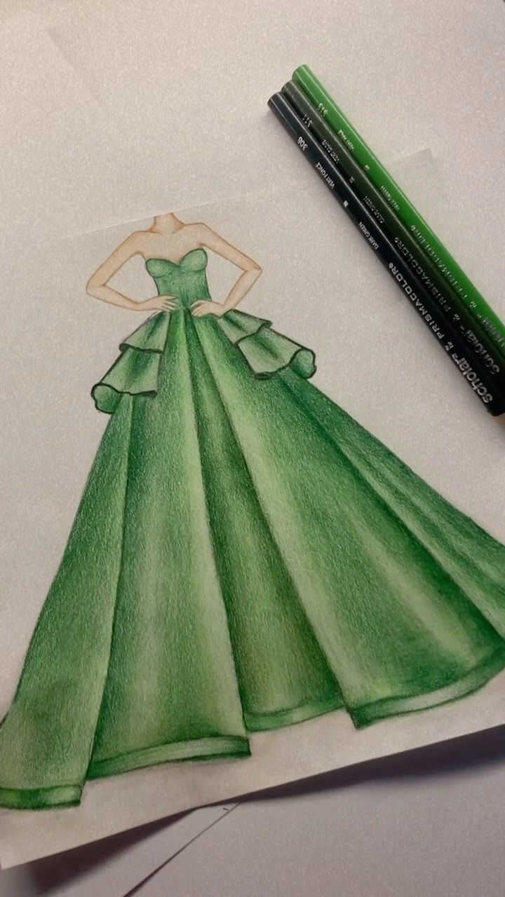 a drawing of a green dress on paper with crayon pencils next to it