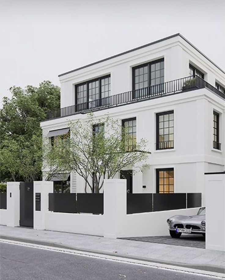 a car parked in front of a two story white building with black balconies