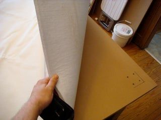 a person is holding up a piece of paper on top of a bed with the sheets pulled back