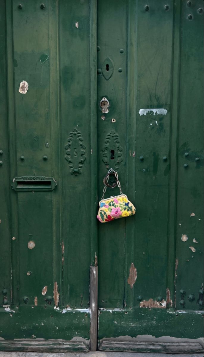 a purse hanging on the side of a green door