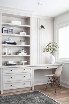 a white desk sitting next to a window in a room with bookshelves and shelves