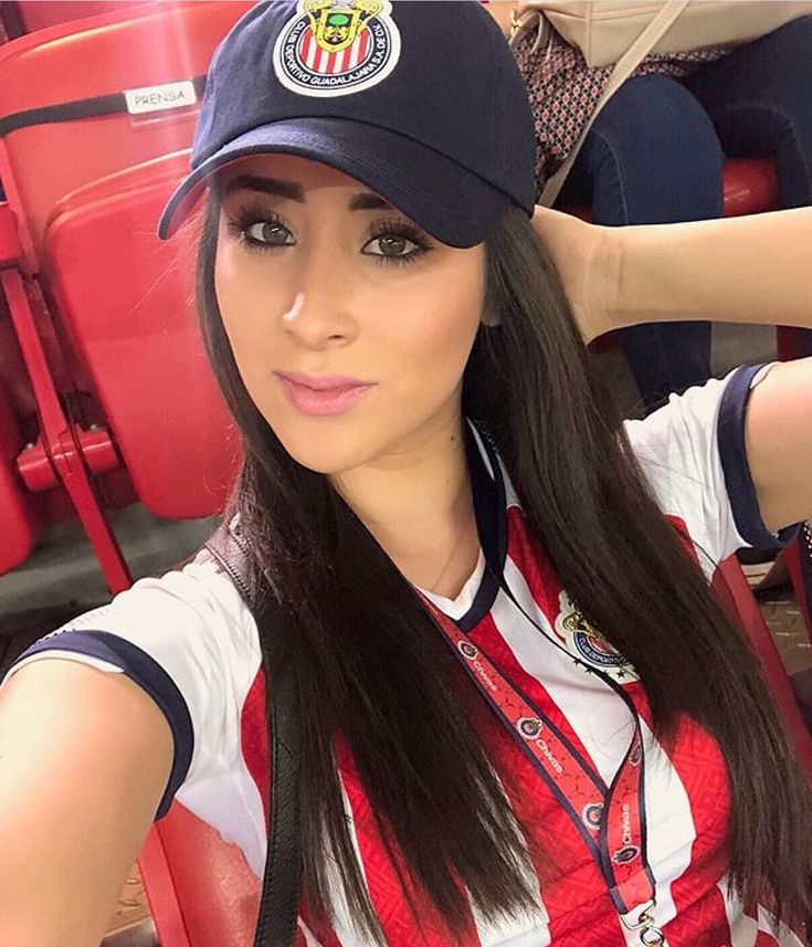 a woman with long hair wearing a hat and sitting in a red chair at a soccer game