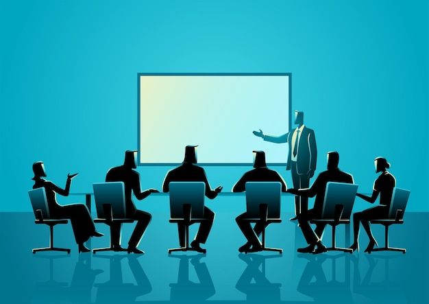 a group of people sitting around a table in front of a large whiteboard with a man giving a presentation