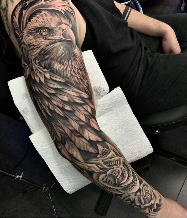 an owl tattoo on the arm is shown in black and grey colors, with roses around it