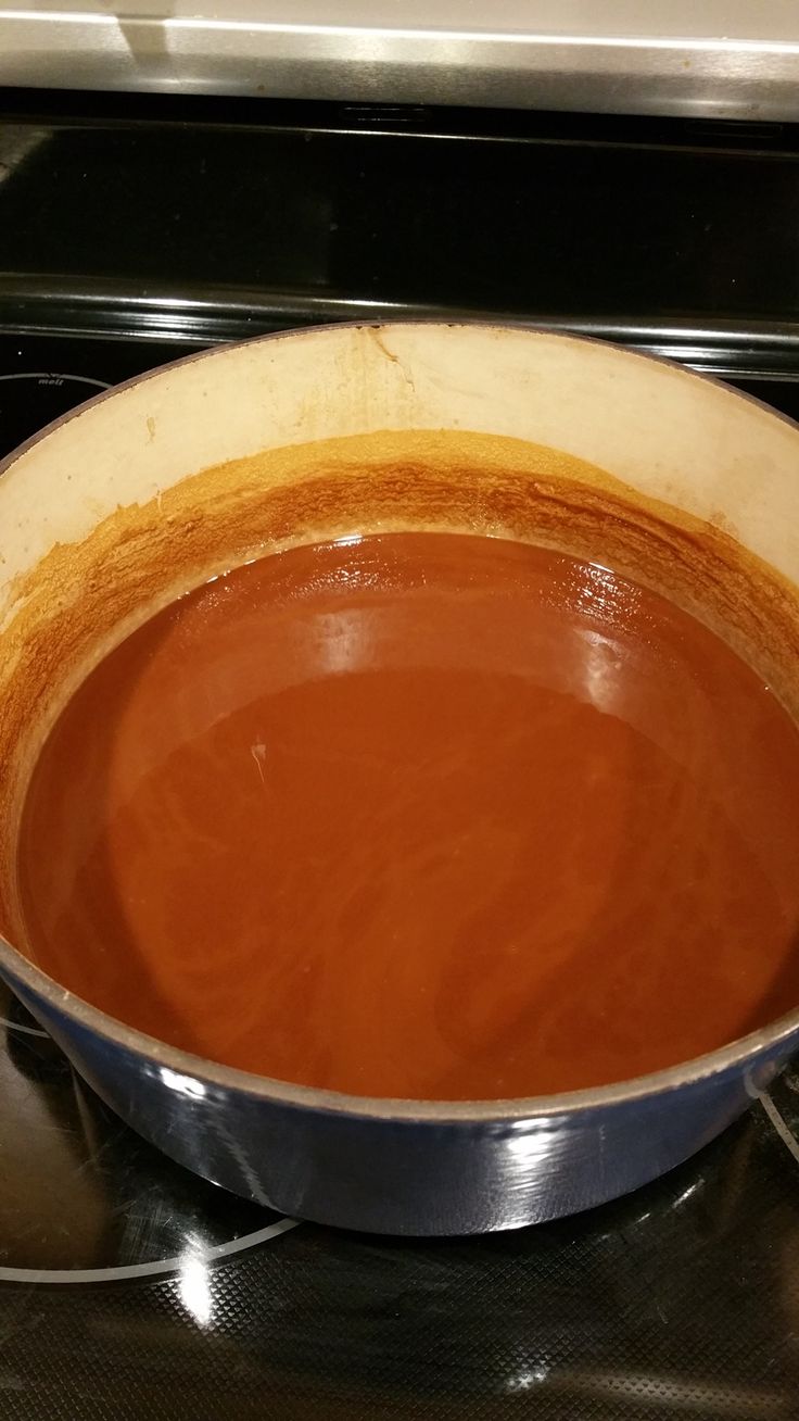 a pot with some brown liquid in it on the stove top, ready to be cooked