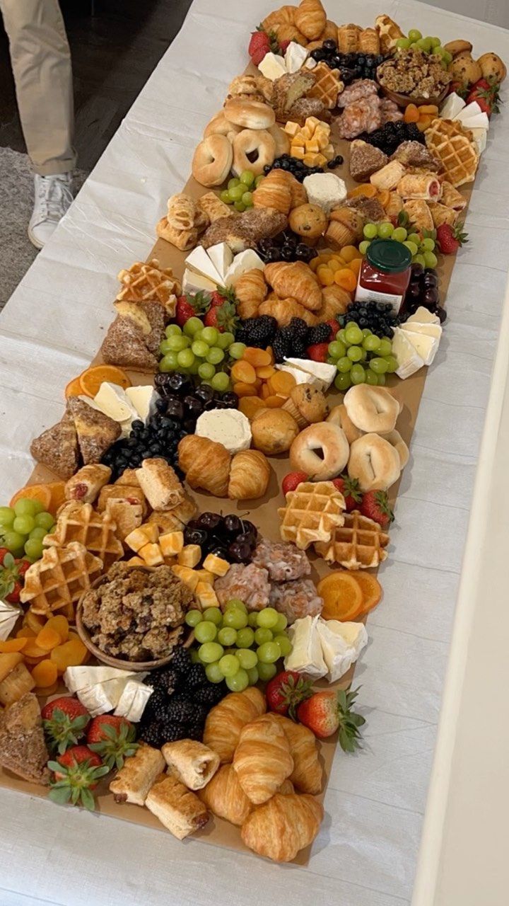 a long table covered with lots of different types of food on top of white paper