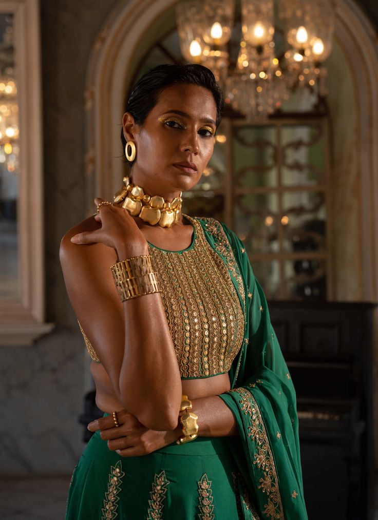 Editor's Note Introducing an exquisite emerald green hand-embroidered lehenga, paired with an organza base dupatta that is heavily highlighted with gold dori and mirror embellishments. The intricate hand embroidery on the lehenga adds a touch of opulence and grace. The mirror embellished blouse complements the ensemble perfectly, adding a sparkling allure. Step into any special occasion with confidence, draped in this stunning emerald green lehenga set that effortlessly combines traditional craf Emerald Green Mirror, Emerald Green Lehenga, Mirror Lehenga, Paulmi And Harsh, Organza Bridal, Blouse Yoke, Organza Lehenga, 1950’s Fashion, Resort Look