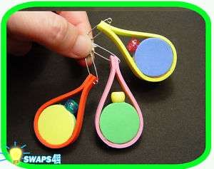 a hand is holding three different colored plastic spoons on a black table with green border