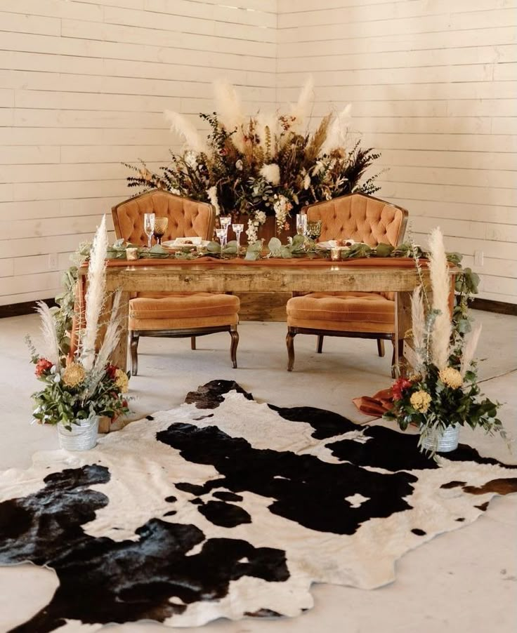 the table is set up with flowers and candles on it, along with two chairs