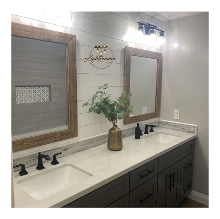 a bathroom with two sinks and mirrors on the wall, one has a potted plant in it