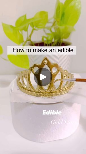 a gold crown ring sitting on top of a white table next to a potted plant