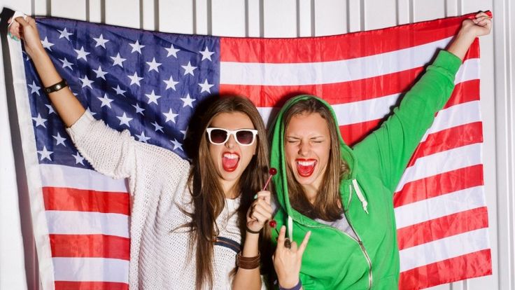 two young women standing in front of an american flag