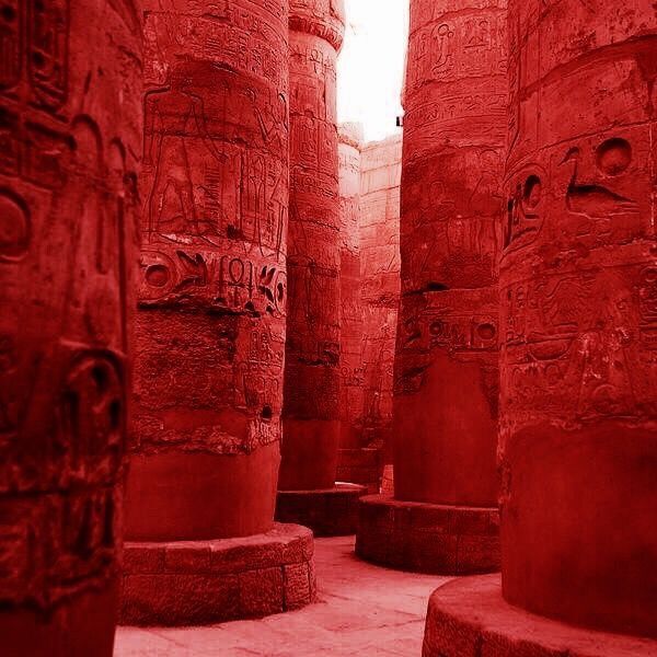 the interior of an ancient egyptian temple with red walls and carvings on it's pillars