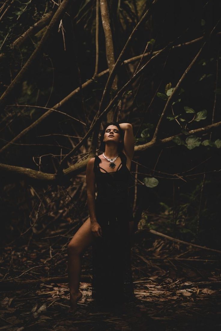 a woman standing in the woods with her hands behind her head