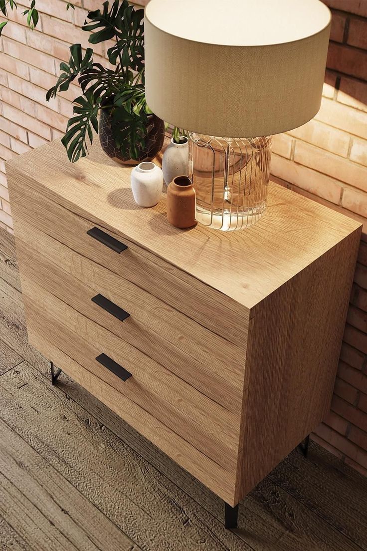 a lamp on top of a wooden dresser next to a potted plant