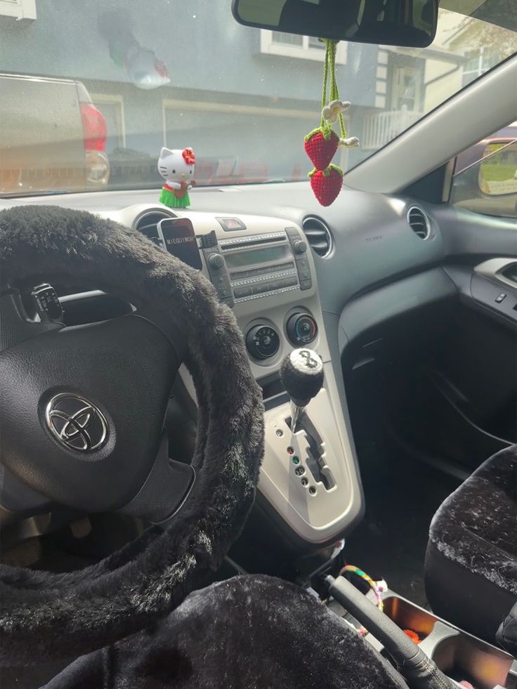 the interior of a car with steering wheel controls and stuffed animals hanging from the dash