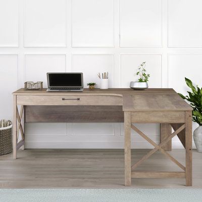 a wooden desk with a laptop and potted plants on it in front of a white wall