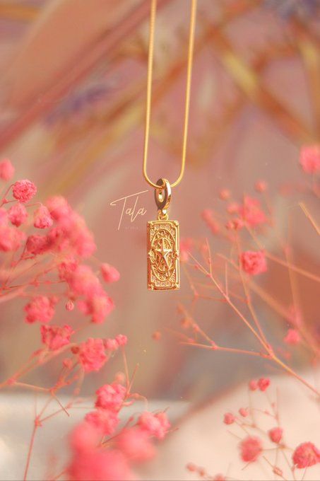 a gold necklace with an image of a woman on it and pink flowers in the background