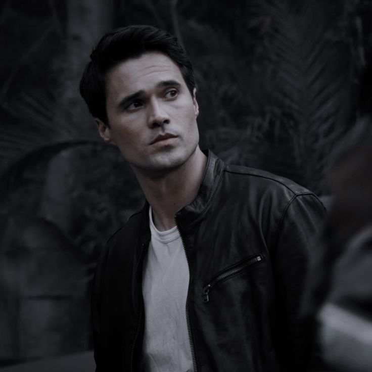 a man in a black leather jacket looking at the camera