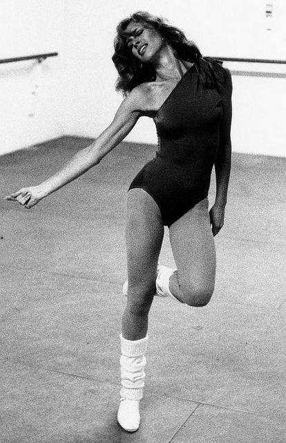 a black and white photo of a woman in a leotard with one leg up