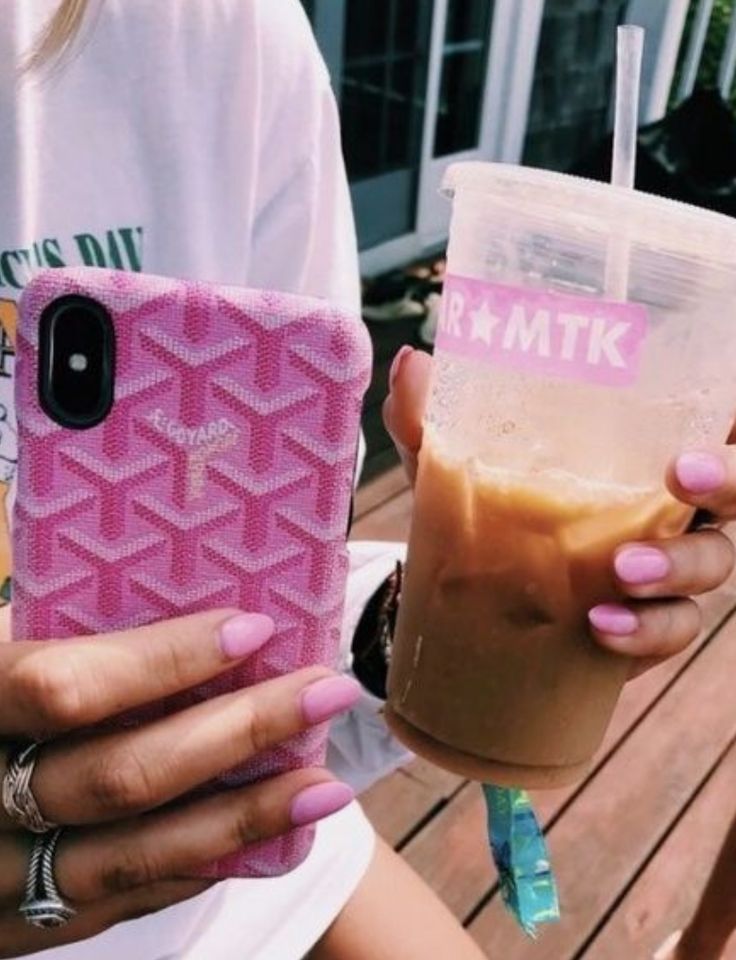 two women holding up their cell phones and drinks