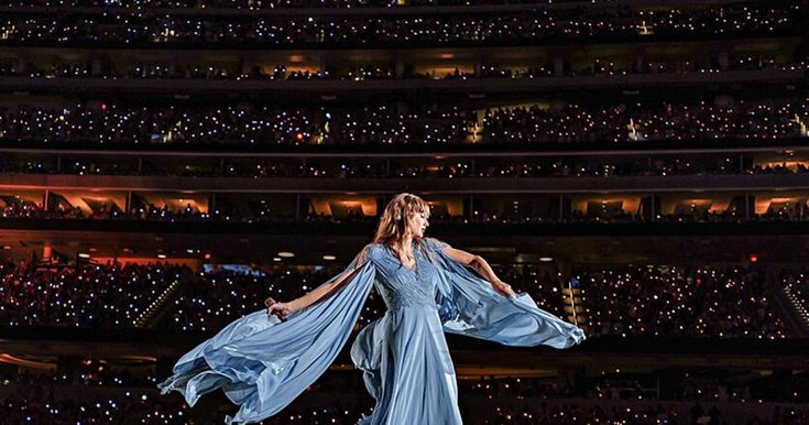 a woman in a blue dress is performing on stage