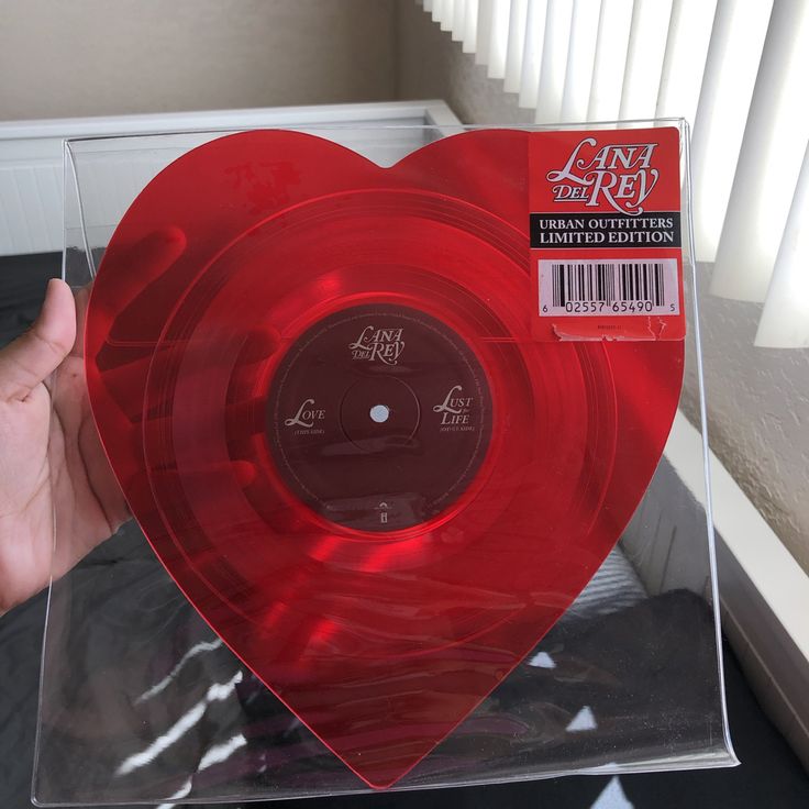 a hand holding a red vinyl record in a heart shaped box with writing on it