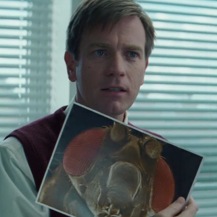 a man holding up an image of a human skull in front of his face and looking at the camera