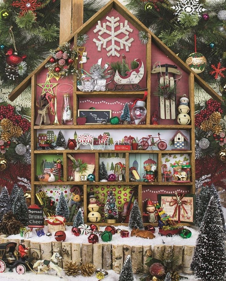 a christmas house with presents and decorations on the table in front of it, surrounded by snowflakes