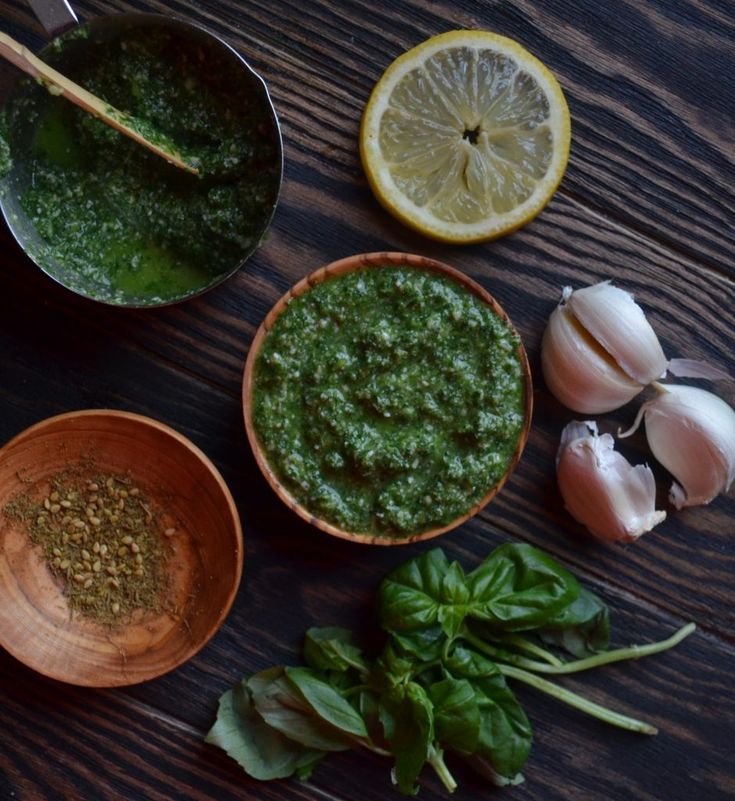 ingredients for pesto sauce displayed on table with lemons, garlic, and basil