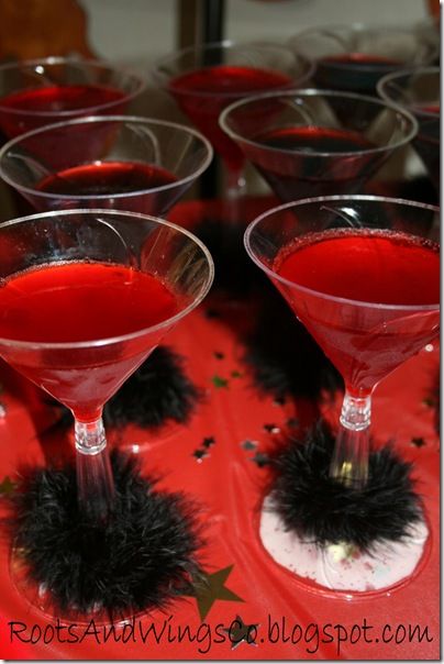 red liquid in martini glasses with black pom - poms