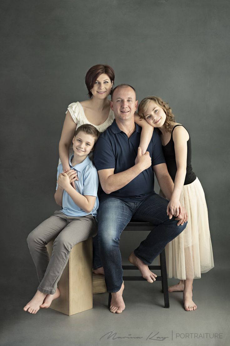 a family poses for a portrait in front of a gray background