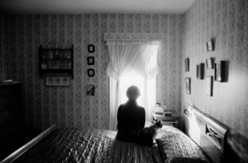 a person sitting on top of a bed in a room with wall papered walls