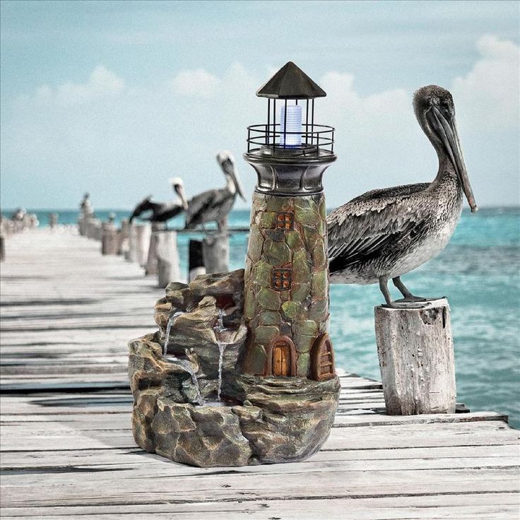 a pelican sitting on top of a wooden dock next to the ocean and a lighthouse